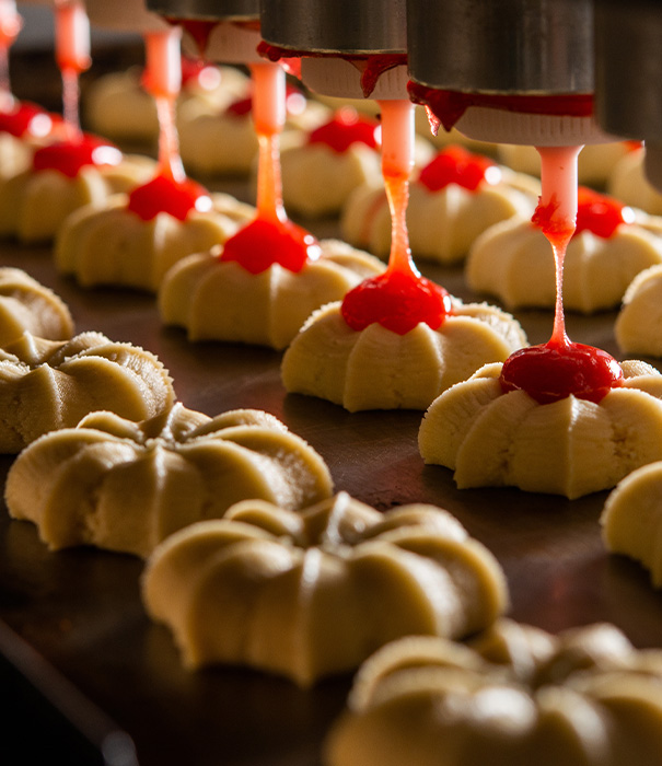 bottles of red hot sauce lined up in a factory setting showcasing production process for hot sauces and condiments with two distinct flavors